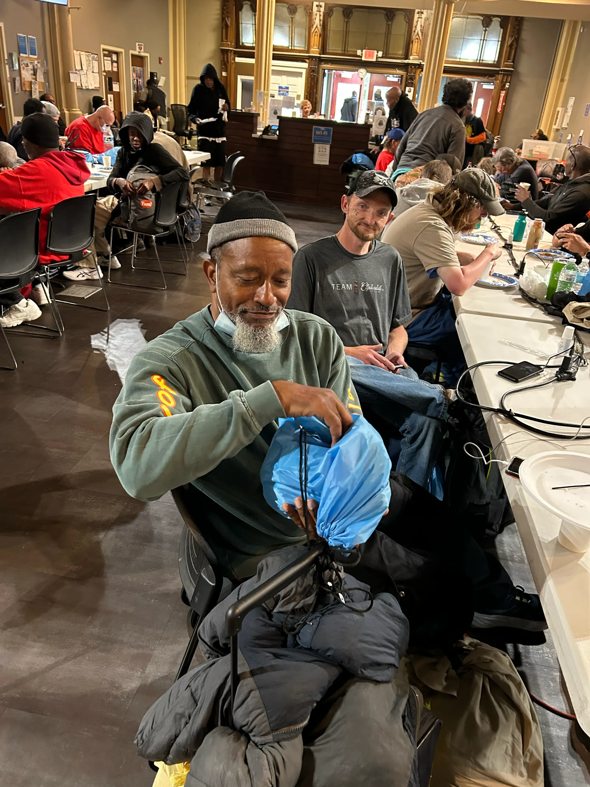 A neighbor opens his blue Touch of Terra backpack at a shelter distribution.